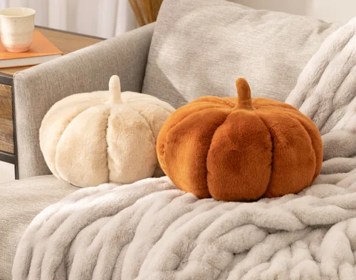Our Custard and Copper pumpkin cushions sitting in a chair together.