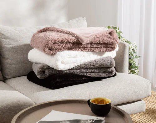 Our Poodle Faux For Throws folded and stacked on a couch.