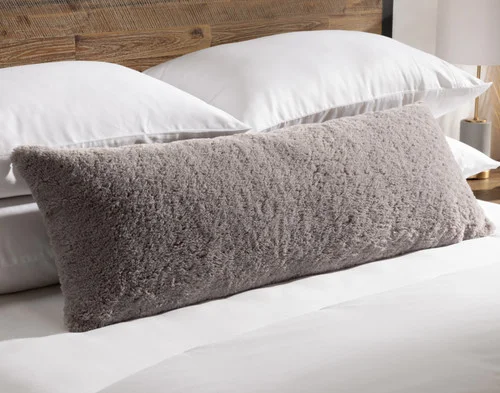 Angled view of our Ashwood Poodle Faux Fur Lumbar Pillow resting on a bed.