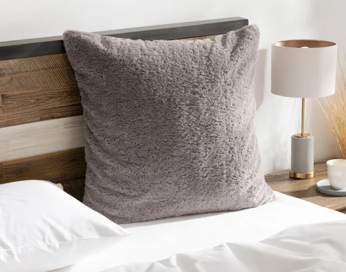 Angled view of our Ashwood Poodle Faux Fur Euro Sham resting on a white bed.