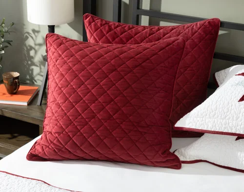 Angled view of our Noelle Wreath Velvet Euro Sham resting on a plain bed.