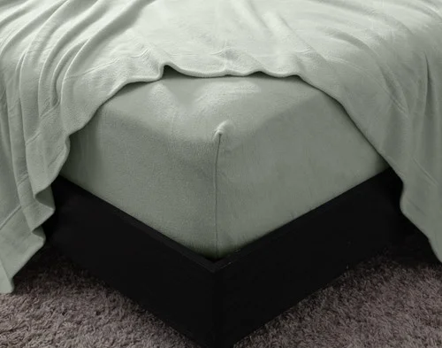 Close-up on the corner of our Cuddle Fleece Sheet Set in Fern with its fitted sheet wrapped around a queen mattress.