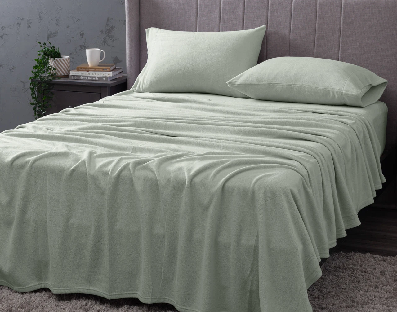 Angled view of our Cuddle Fleece Sheet Set in Fern fitted over a queen bed in a dark grey bedroom.