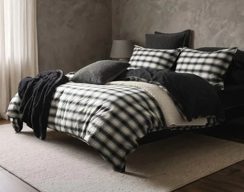 Angled view of our Bailey Duvet Cover Set dressing a queen bed with black accessories.
