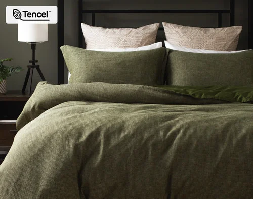 Front, off-centre view of our Greenwood Duvet Cover dressing a queen bed in a dark room.