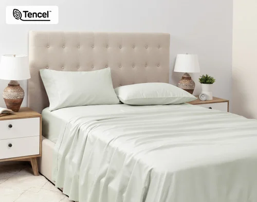 Angled view of a queen bed dressed in our Eucalyptus Luxe Sheet Set in Oyster.