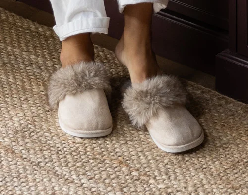 Close-up of our Faux Fur Plush Slippers in Dune being worn in a living room.