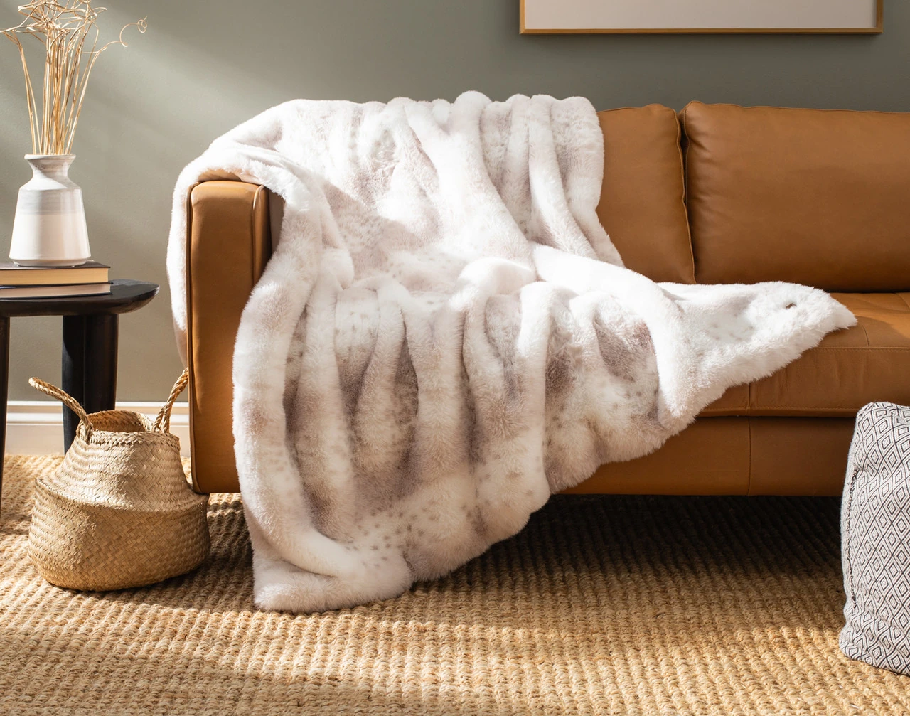 Our Animal Faux Fur Throw - Snow Leopard draped over a brown couch.