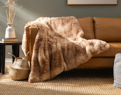 Our Animal Faux Fur Throw - Fawn draped over a brown couch.