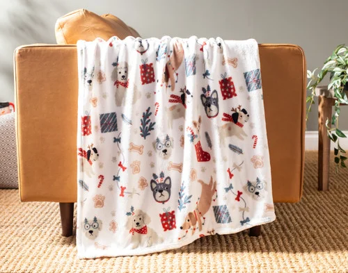 Our Holiday Fleece Throw - Cozy Canines draped over a brown couch.
