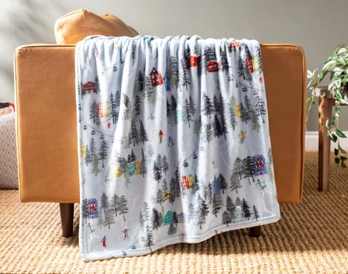Our Holiday Fleece Throw - Alpine Retreat draped over a brown couch.