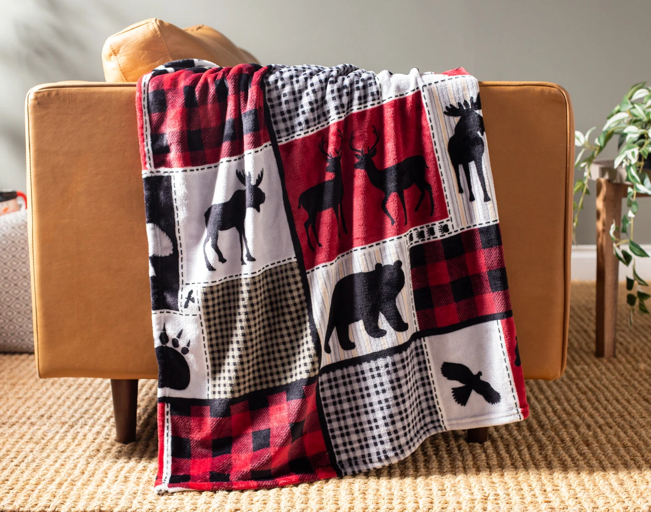 Our Holiday Fleece Throw - Cabin Comfort draped over a brown couch.