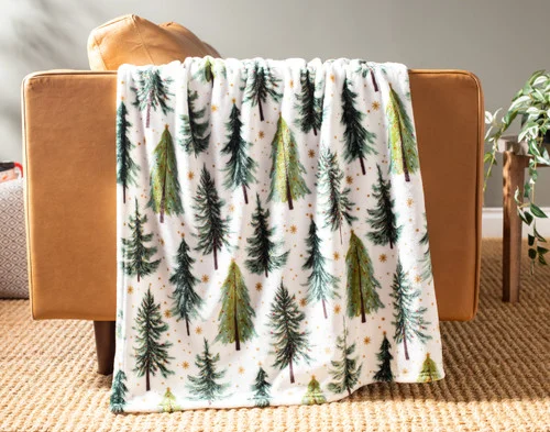 Our Holiday Fleece Throw - Merry Pines draped over a brown couch.