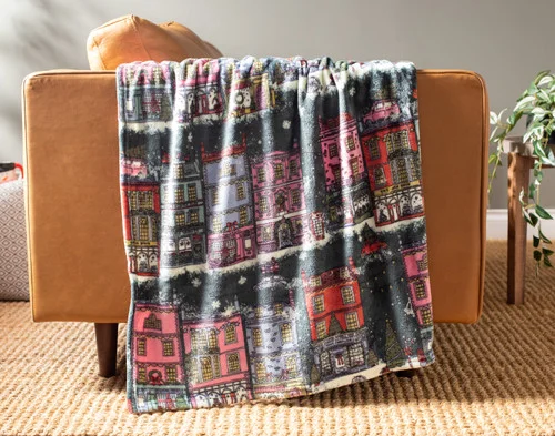 Our Holiday Fleece Throw - Festive Grove draped over a brown couch.