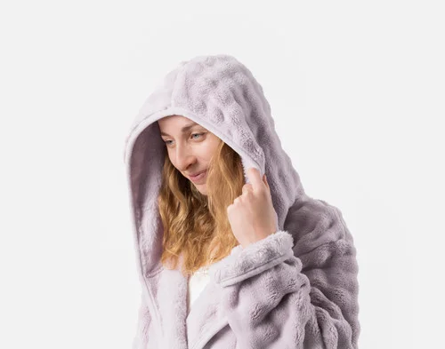 Woman pulling the hood of our Sage Mini Bubble Hooded Bathrobe over the top of her head.