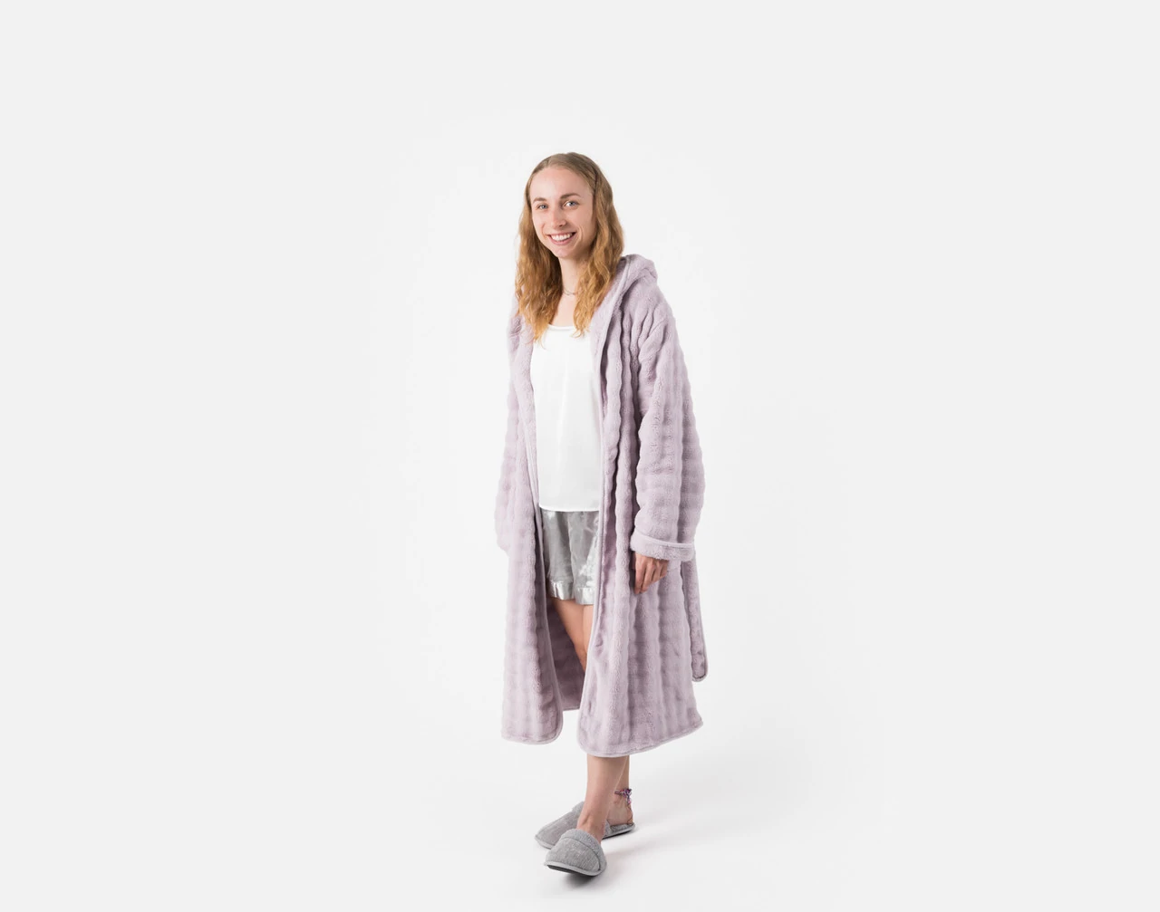 Woman wearing our Sage Mini Bubble Hooded Bathrobe while standing in a white room.