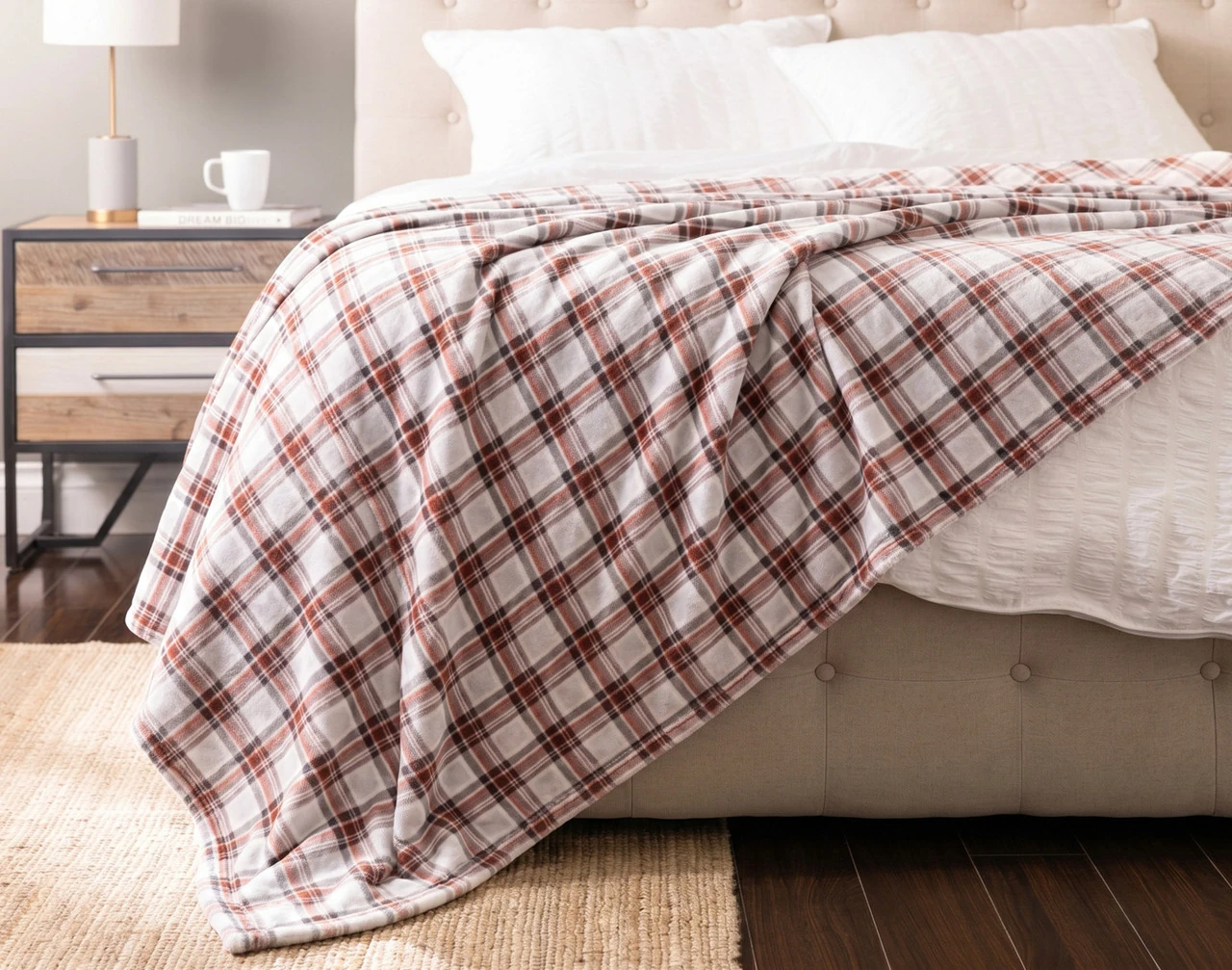 Front view of our Brome Plaid Blanket draped over a white bed.