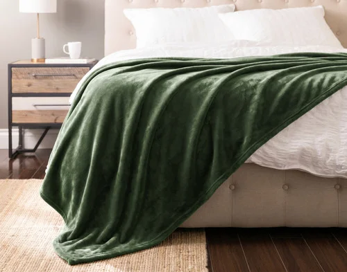Front view of our Fir Cashmere Touch Blanket draped over a white bed.