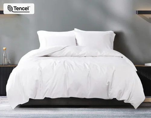Front view of our Eucalyptus Luxe TENCEL™ Lyocell Duvet Cover in White dressed over a queen bed with grey sheets in a white modern bedroom.