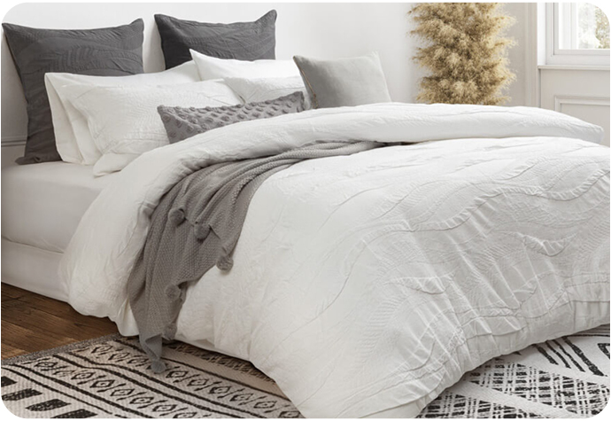Our Anira Bedding Collection features a white duvet cover with a textured wave pattern and coordinating white pillow shams