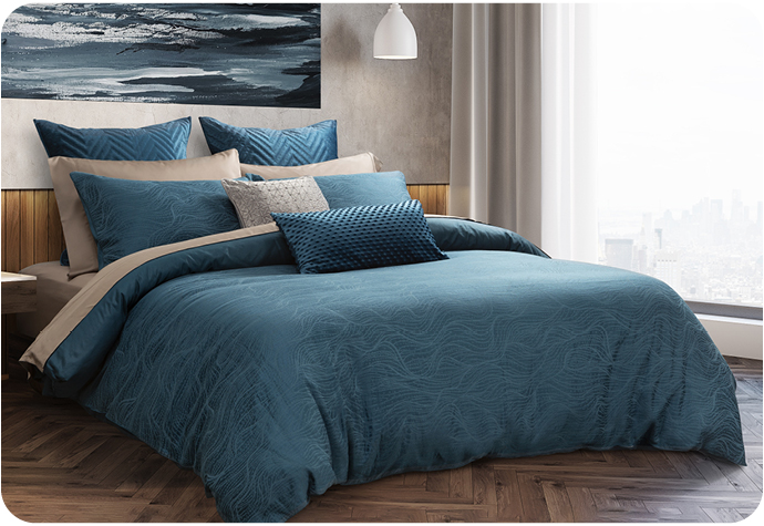 Dark blue bedding set with light sheen on a bed with an artwork above and window in view