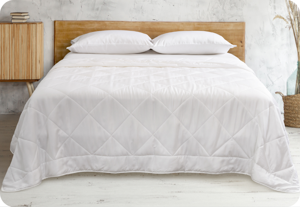 A bed dressed in a light summer duvet.