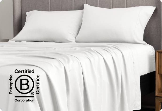 Better B Corp bedding A white sheet set dressing a bed with the B Corp logo.