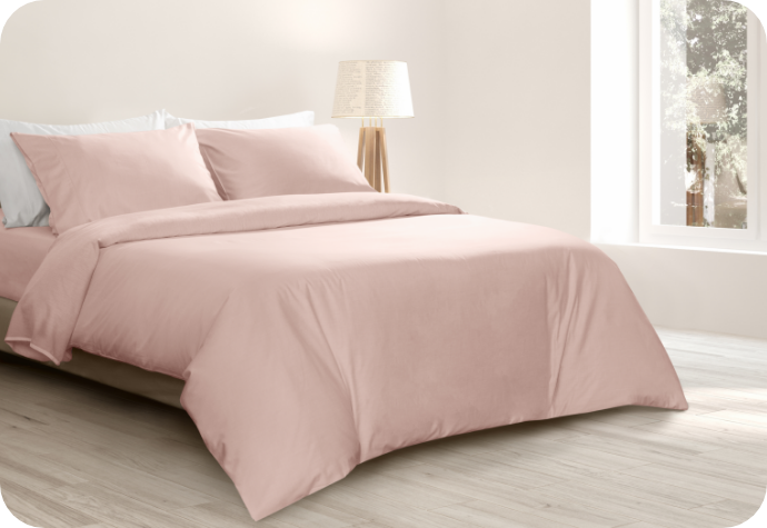 A queen bed dressed in a pink sheet set.