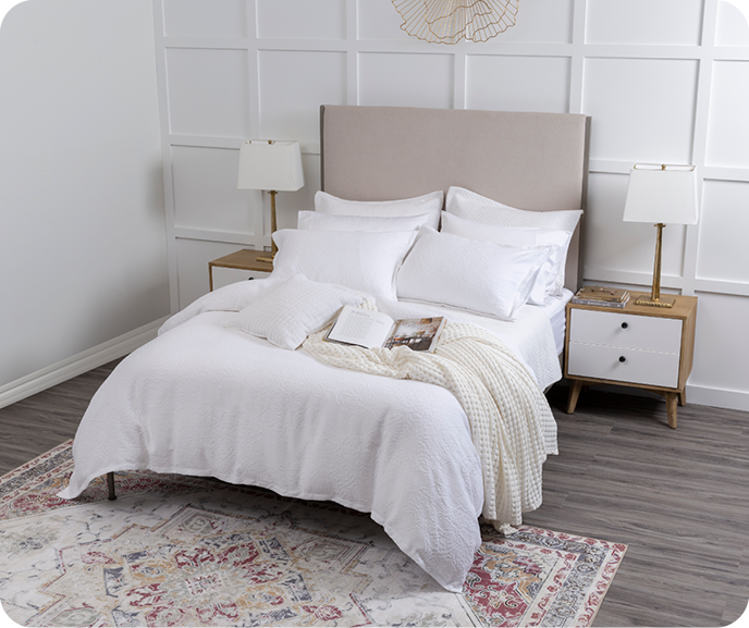 The Portugal Reserve Collection's white Corinthia Duvet Cover and matching pillow shams paid with a white throw blanket on a queen bed in an elegant bedroom. The Portugal Reserve Collection's white Corinthia Duvet Cover and matching pillow shams paid with a white throw blanket on a queen bed in an elegant bedroom.