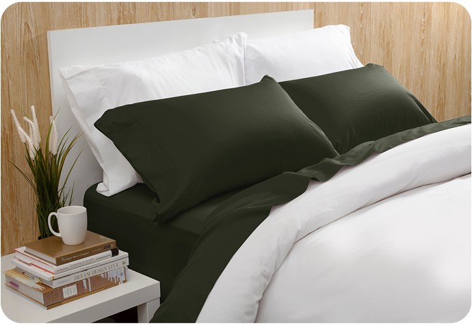 Our Beechbliss Sheet Set in Rainforest Green dressed over a white bed in a light wooden bedroom.