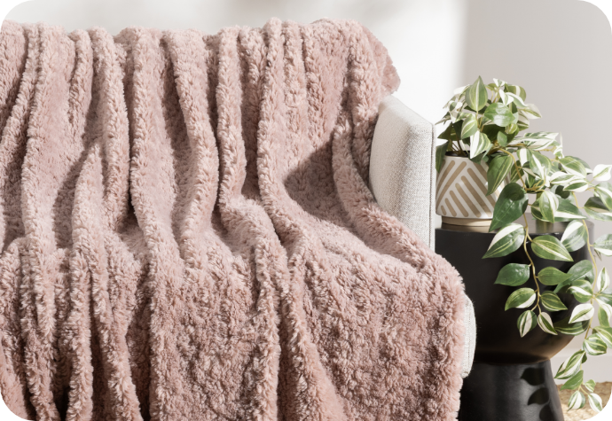 Our Poodle Faux Fur Throw - Dusty Rose Our Poodle Faux Fur Throw in Dusty Rose laying on a couch.