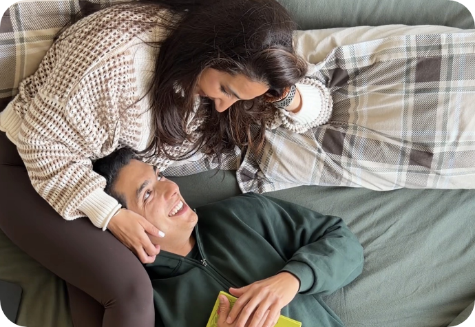 A couple enjoys time in bed together on green sheets. 