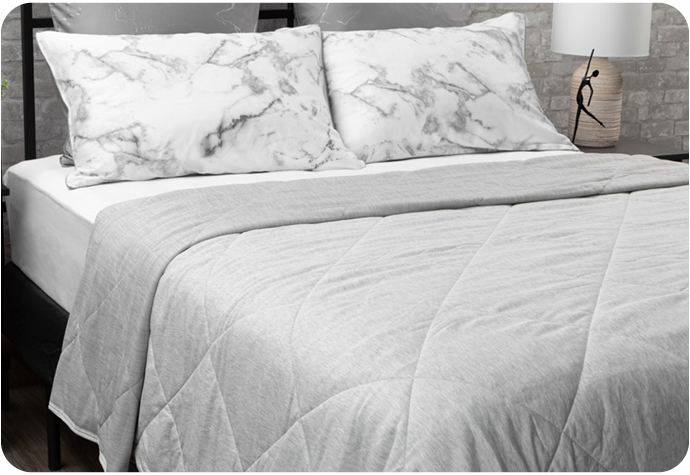 Our Cool Touch Blanket in Grey shown on a bed with coordinating pillowcases. 