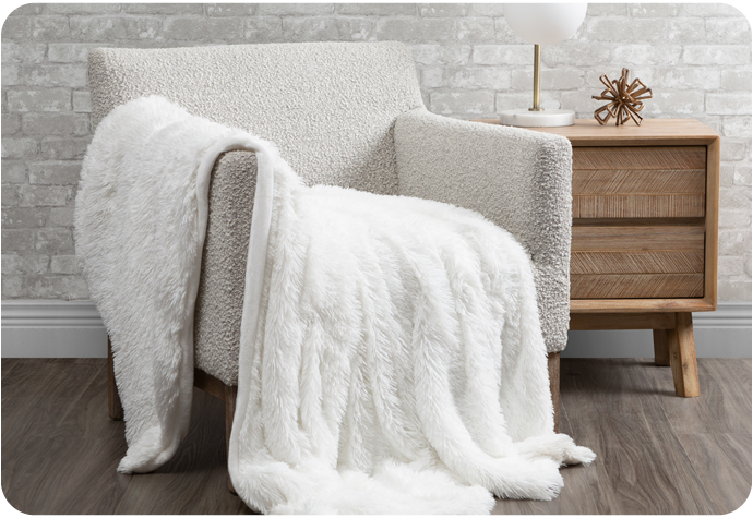 Our Frosted Shaggy Throw in Pure White shown draped over an armchair.