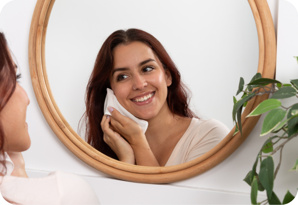 A woman using our silk face cloths in the mirror