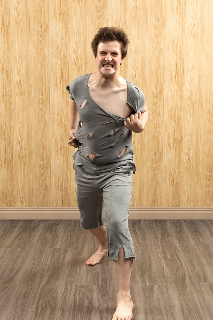 Man with fluffy hair and an angry expression tearing out of his shredded loungewear like a werewolf.