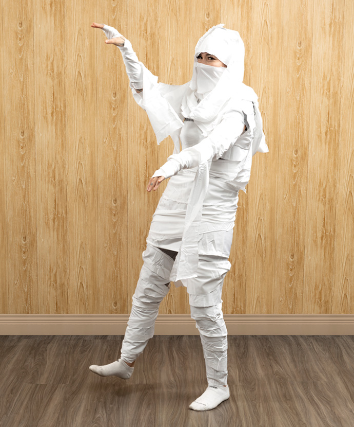 Woman dressed in a mummy costume made from white fabric scraps.