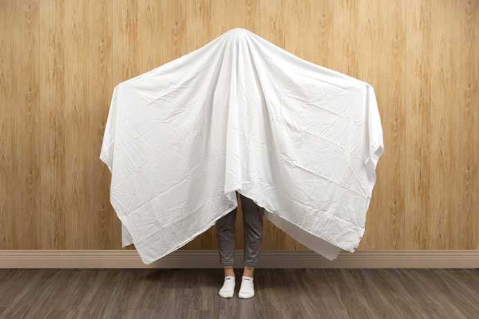 Womanwith a full white flat sheet draped over her head to show its size.