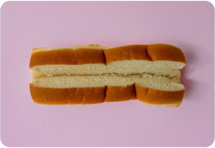 Hot dog bun on a pink background. Time to get creative with these creative hot dog recipes.