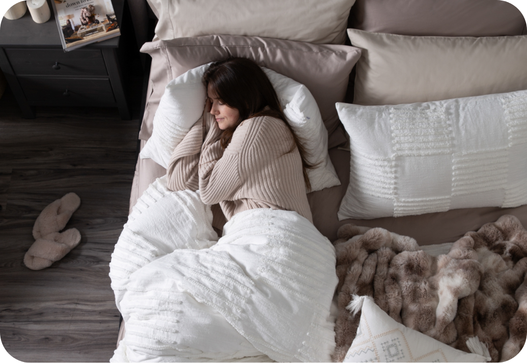Woman curled up under our Caro Duvet Cover and accessories.