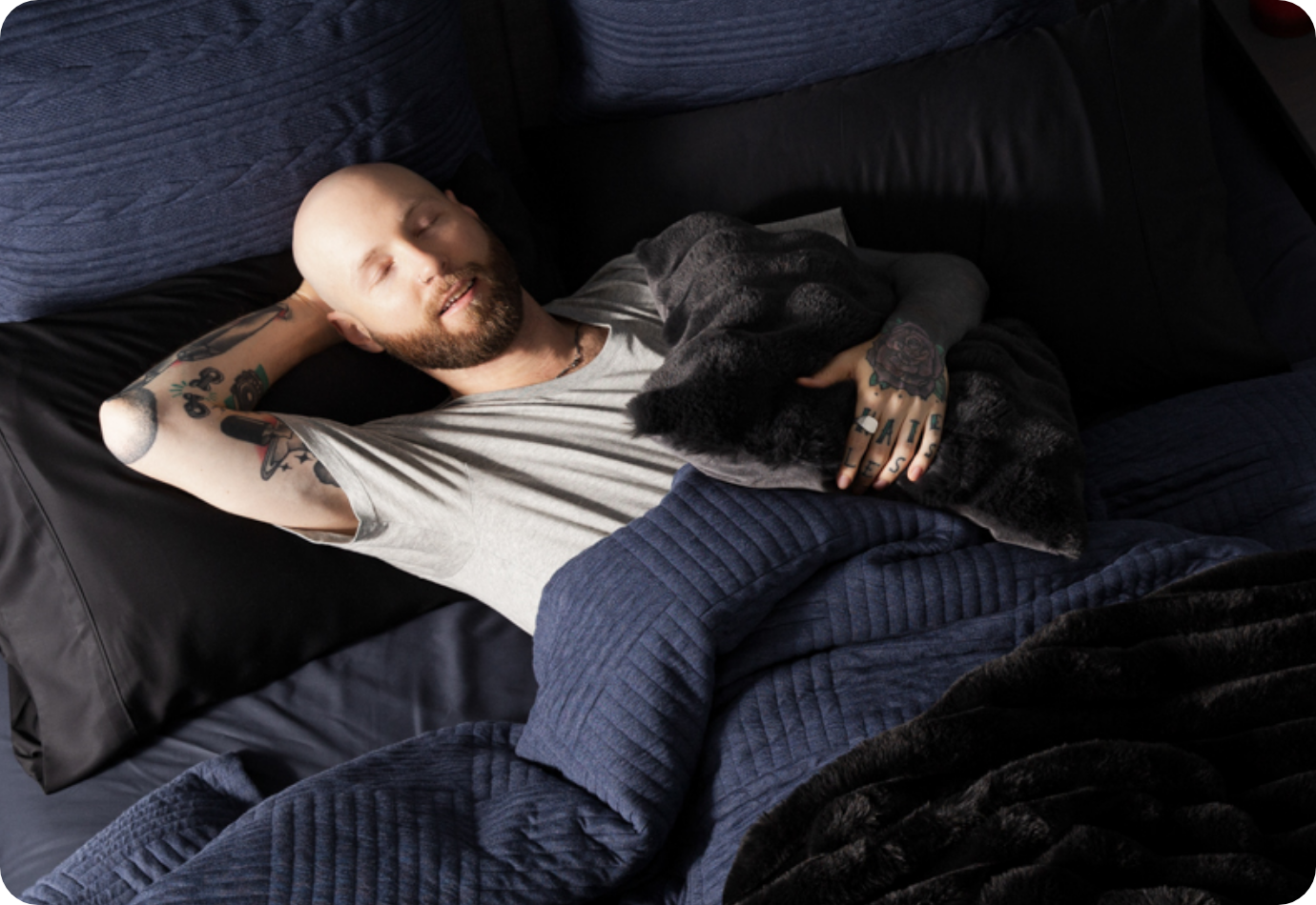 A man sleeping in a bed dressed in our Kye Duvet Cover Set.